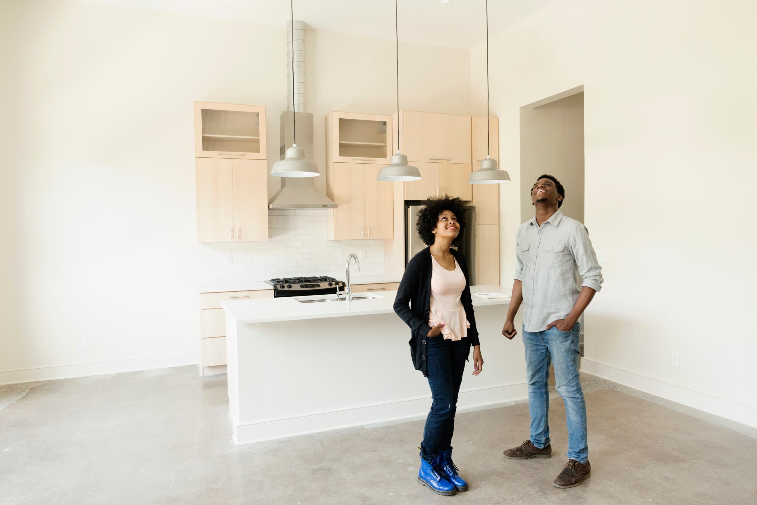A couple smiling at each other over mugs in a kitchen