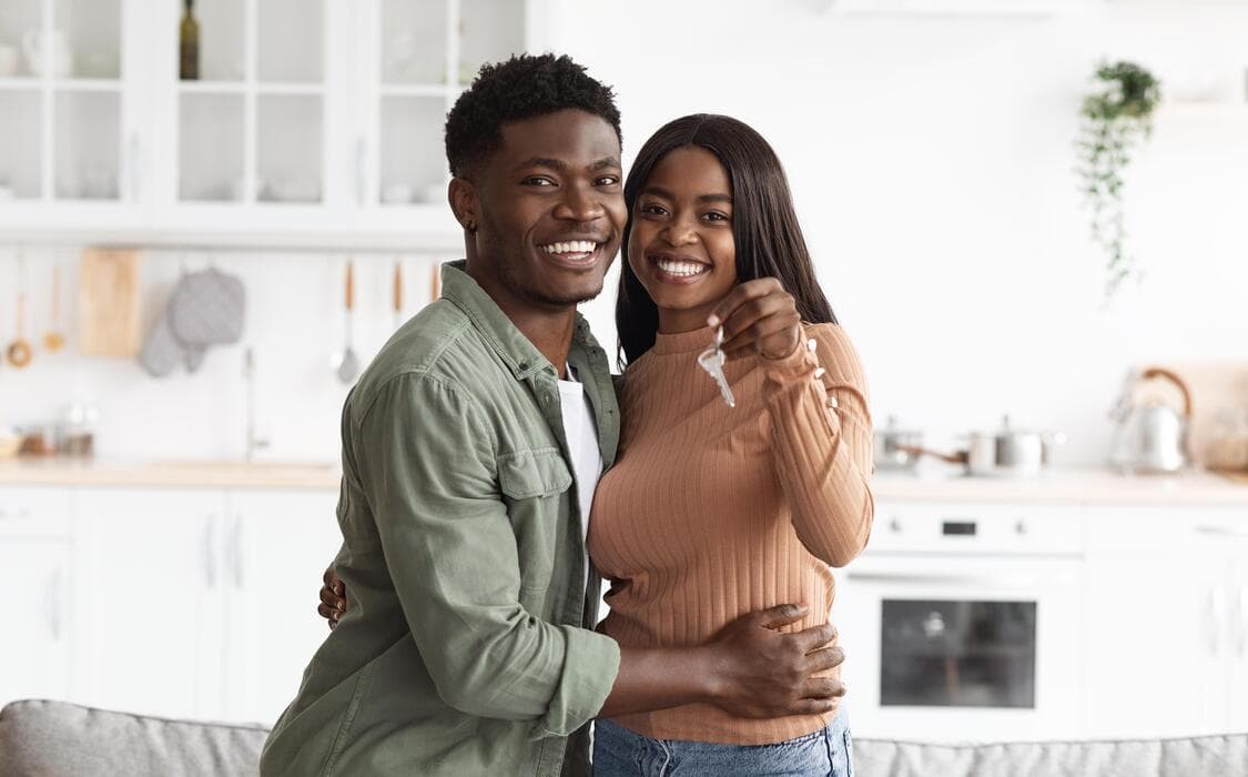 A couple hugging and holding the keys to their new home