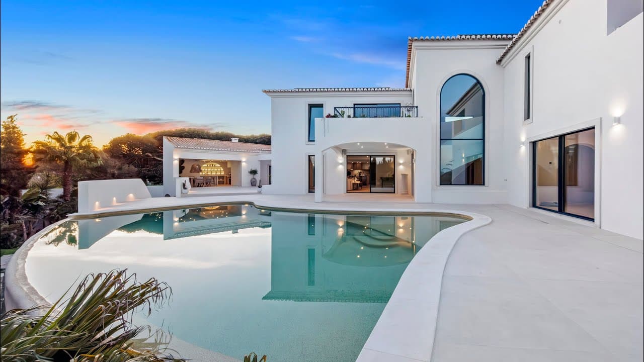 A modern two-story house with a stone facade and a glass balcony